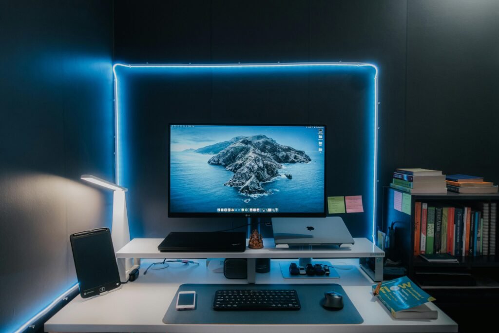 Stylish home office desk setup featuring LED lights, monitor, laptop, and essentials for a productive workspace.